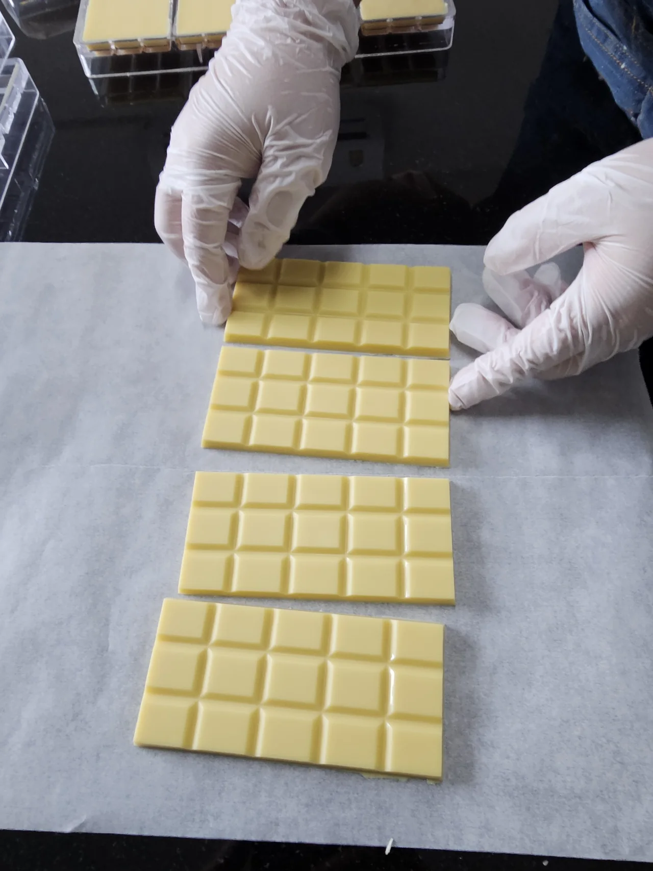 Gloved hands handling chocolate as it is released from a mould.